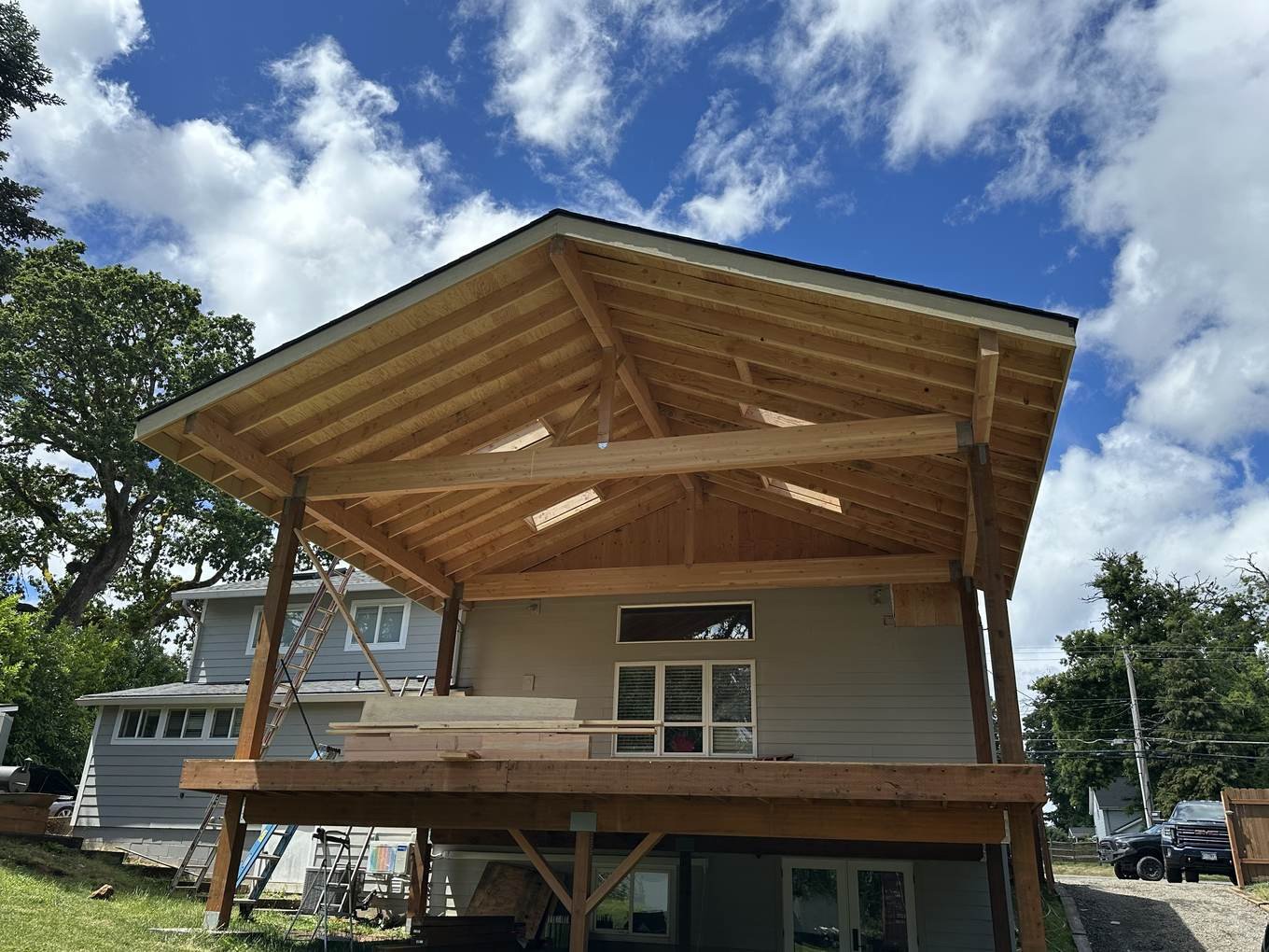 Exposed timber rafters on a vaulted covered structure framed by Paulinson Construction