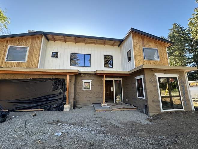 Farmhouse style custom home with vertical cedar siding and multiple roof planes